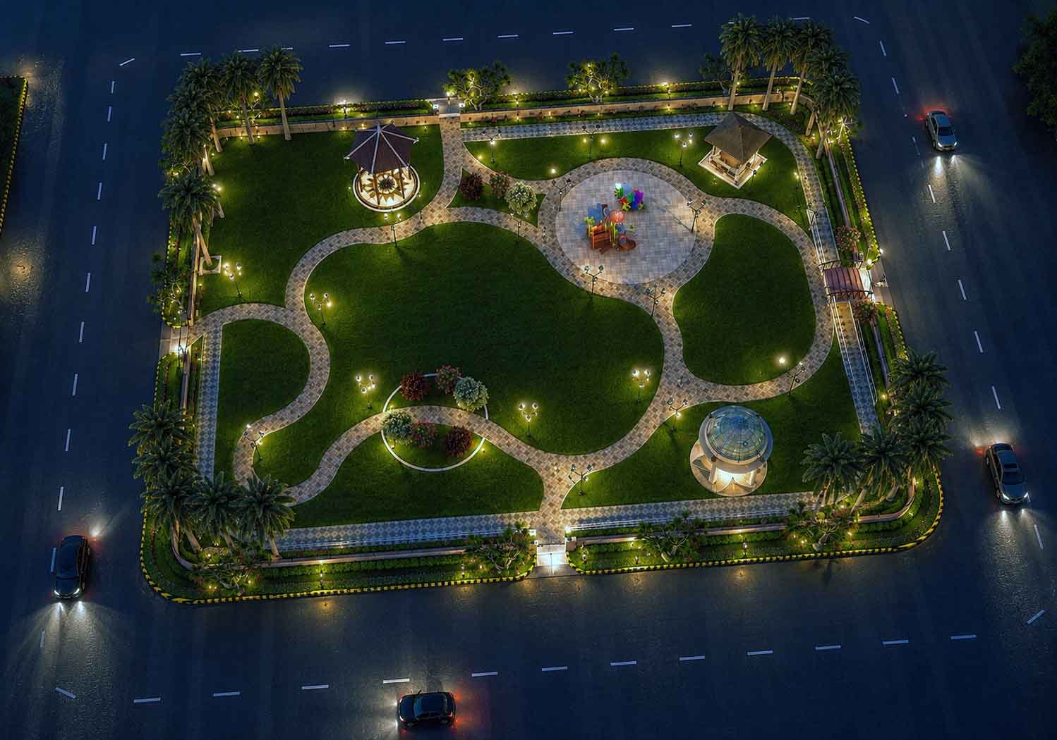 Aerial night view of a landscaped community park illuminated with pathway lights, glowing gazebos, and palm trees, surrounded by roads with passing cars.